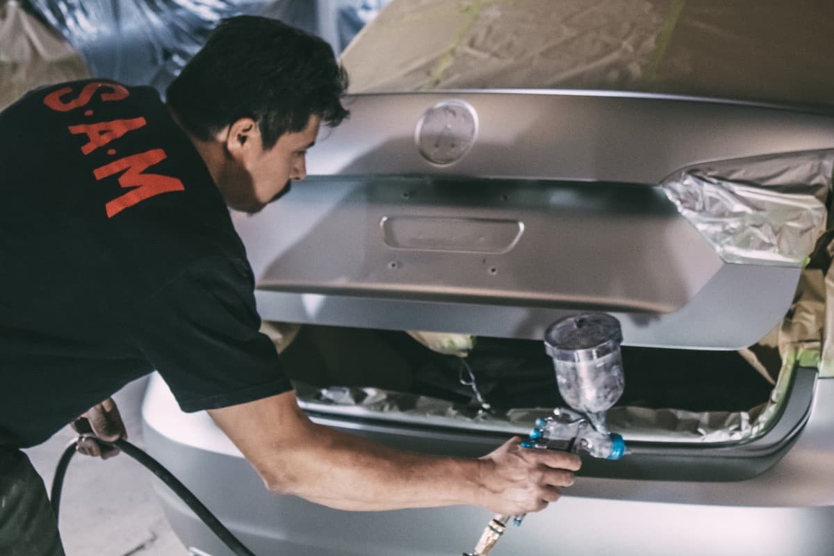 Técnico aplicando pintura automotriz con pistola para acabado uniforme