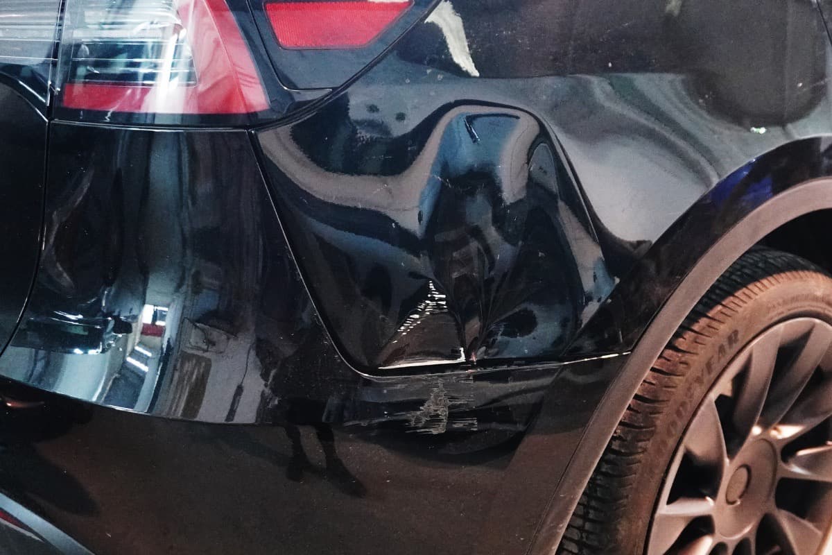 Golpe pronunciado en salpicadera trasera antes de reparación de carrocería y enderezado profesional